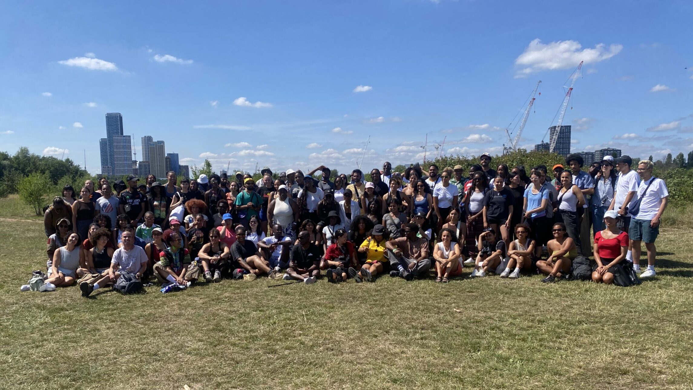 the picture shows a group of people in a park posing in a group together for the photo