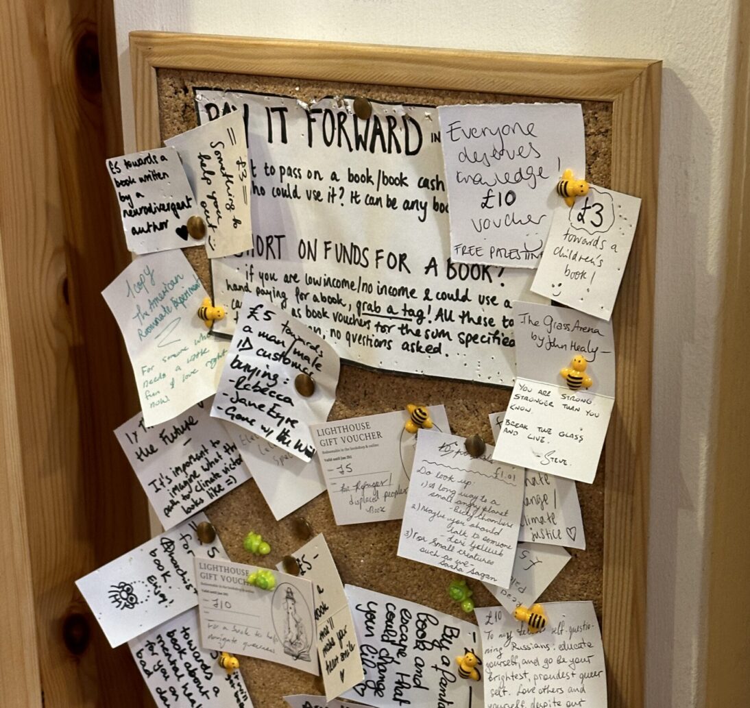 In the image there is a cork noticeboard with lots of white notices pinned to the board with yellow and black bee pins.