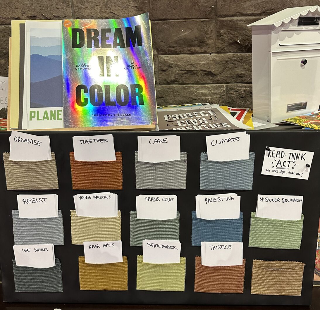 The image shows a notice table with lots of felt pouches. There are white action cards poking out of each one, with labels such as care, climate, organise.