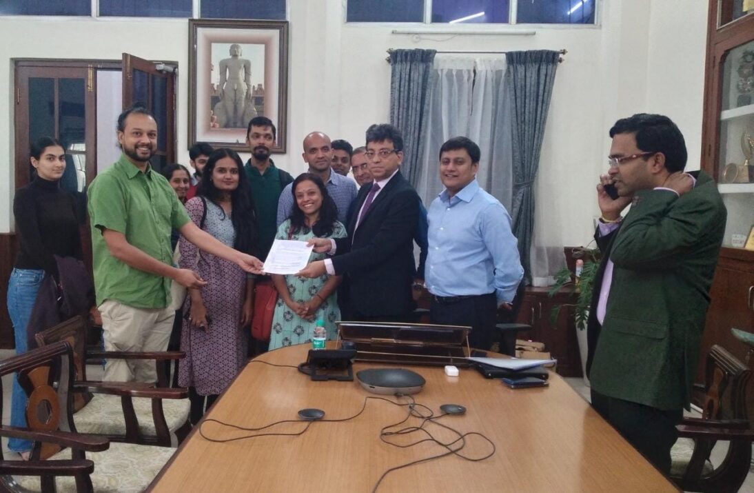 the image shows a group of people in an office room handing over an important document