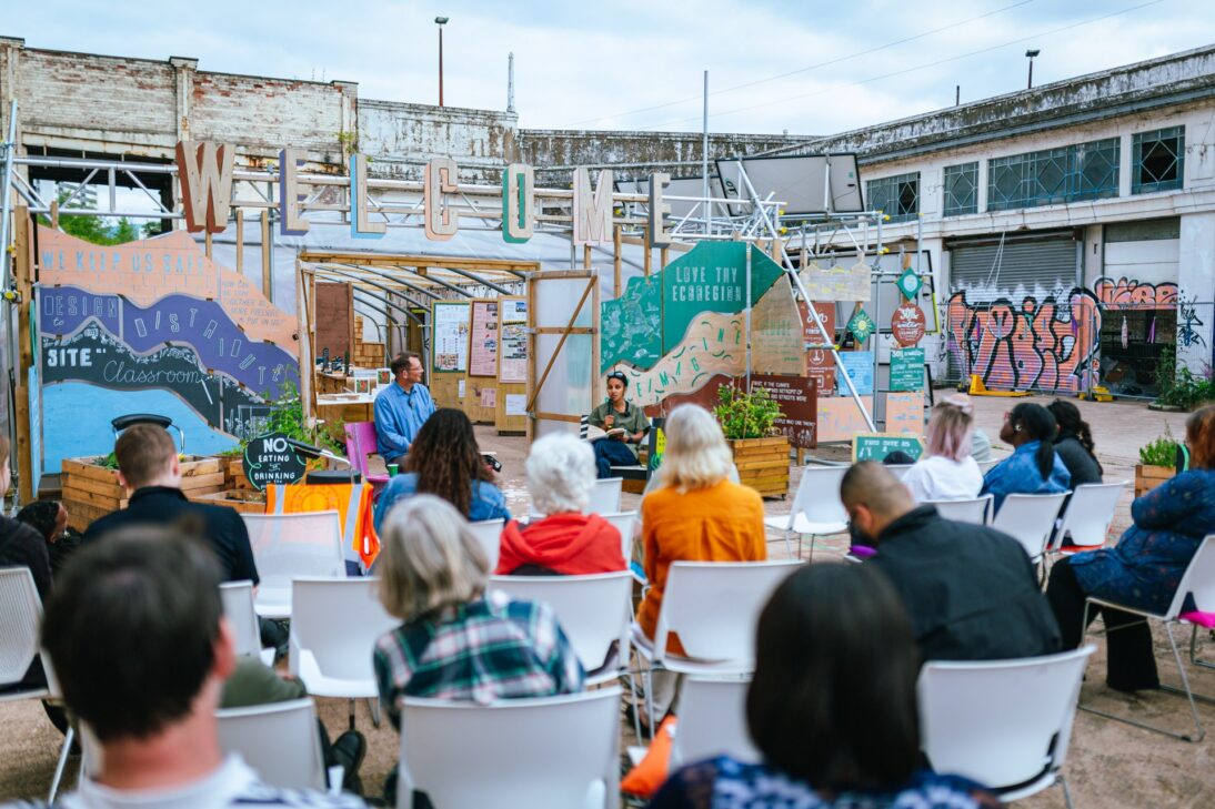the image shows a group of people sat listening to a panel discussion at a Civic Square event.