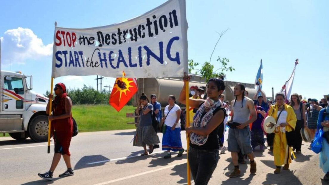 the image shows a group marching in protest. they are holding a banner that reads