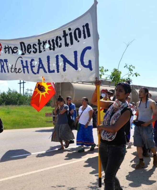 the image shows a group marching in protest. they are holding a banner that reads 